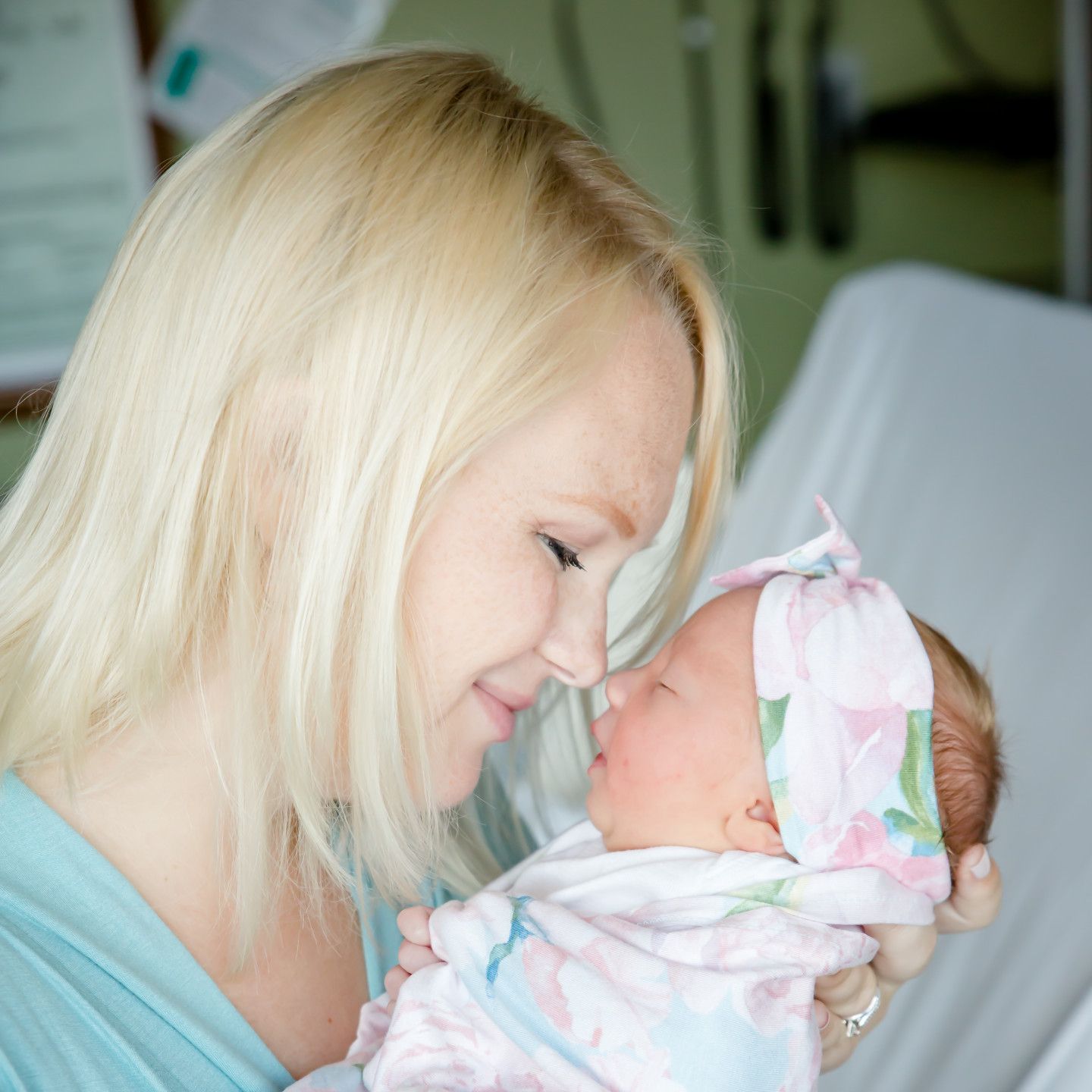 Woman holding newborn, looking at the baby lovingly in a hospital setting.