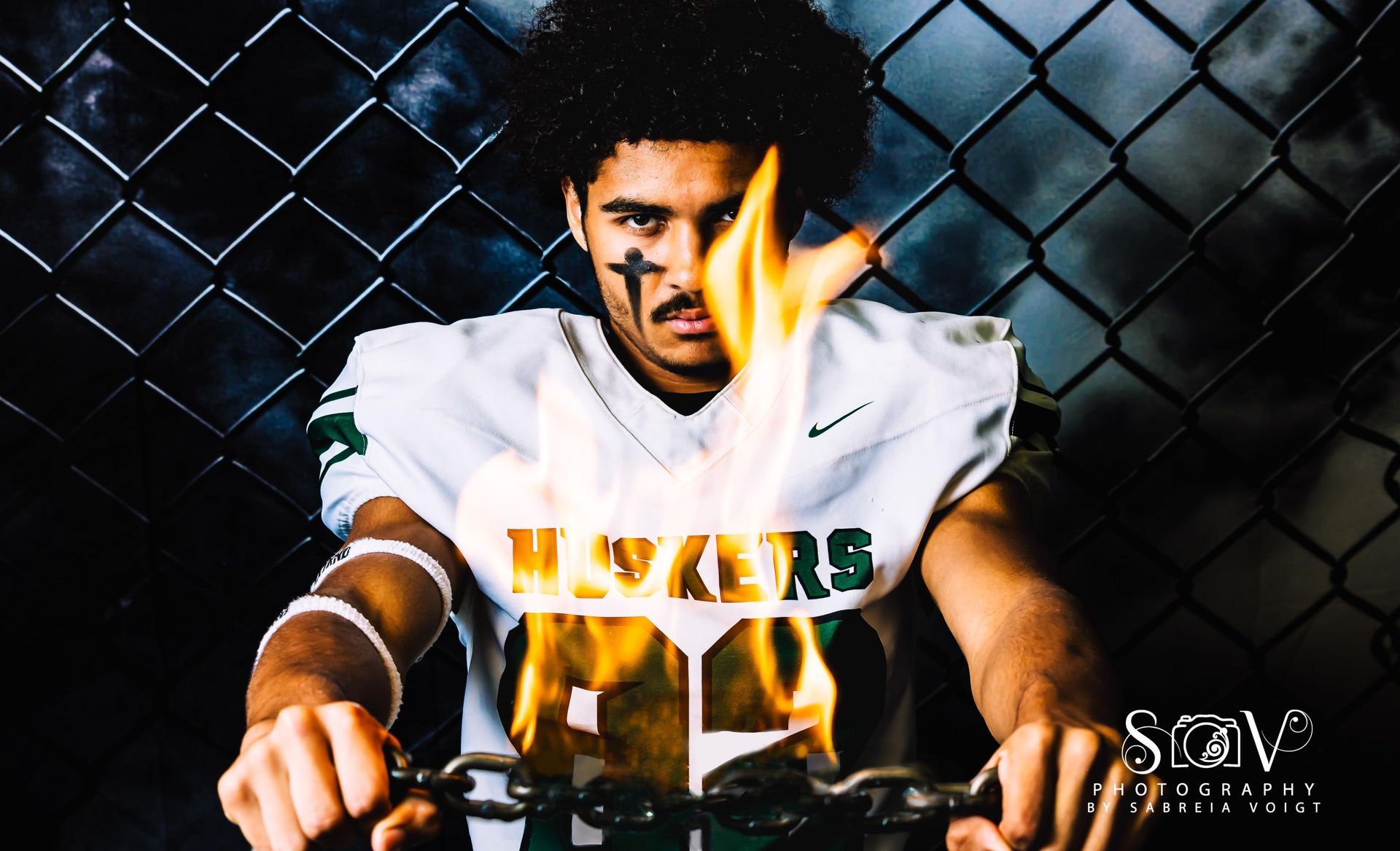 Football player holding burning chain, wearing jersey that says 