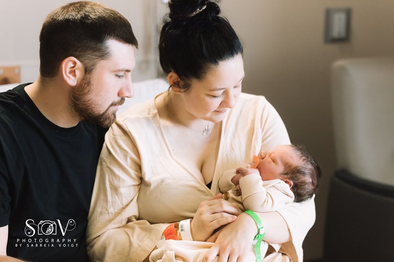 Parents gazing lovingly at newborn in hospital room.