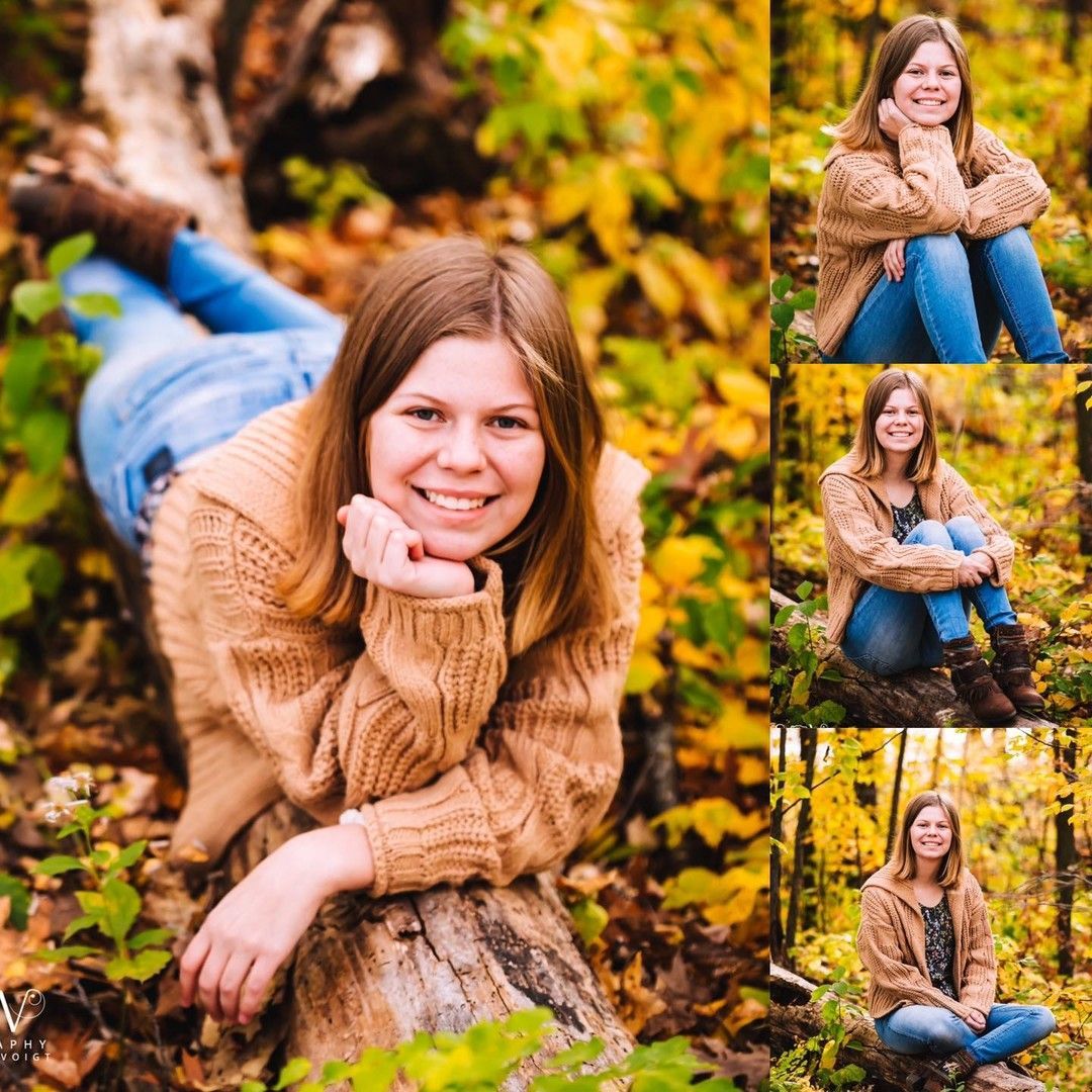 Woman in brown sweater and jeans smiles while lying on a log in a fall forest.