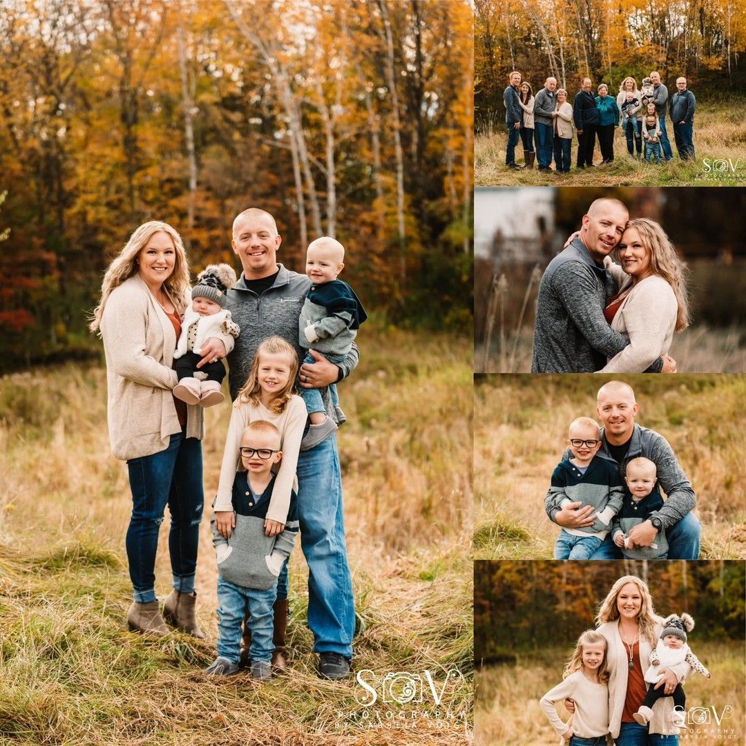 Family portrait in autumn field. Parents, two children, and baby smiling. Colorful foliage in background.