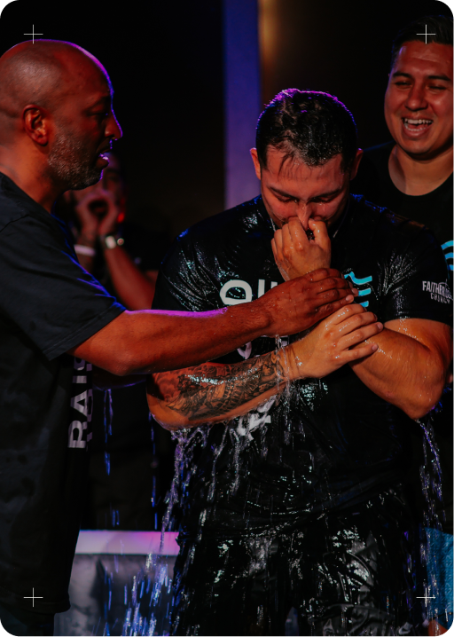 Wet fighter being congratulated after a match, with water splashing under arena lights