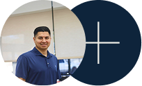 Man in navy polo standing beside a dark blue circle with a white plus sign.