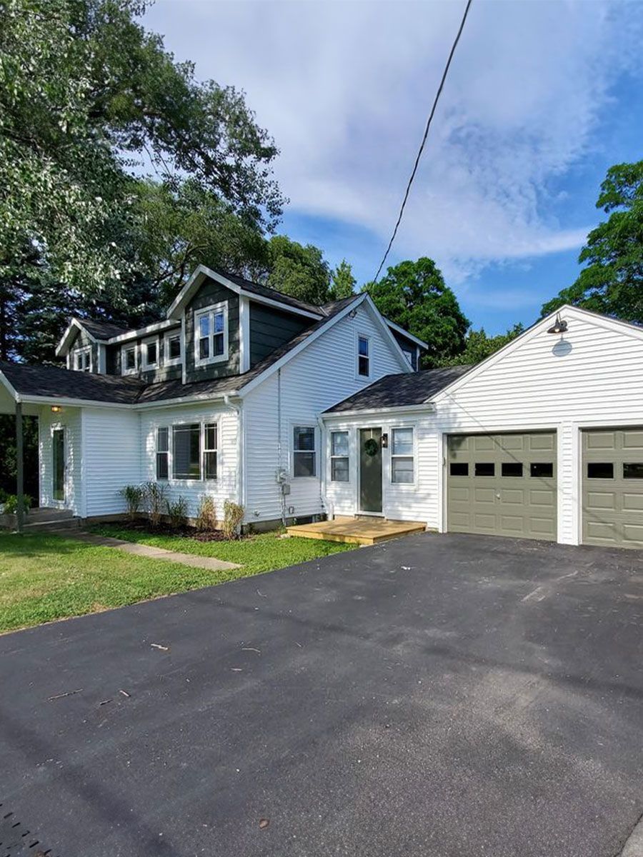 A white house with a garage and a driveway in front of it.