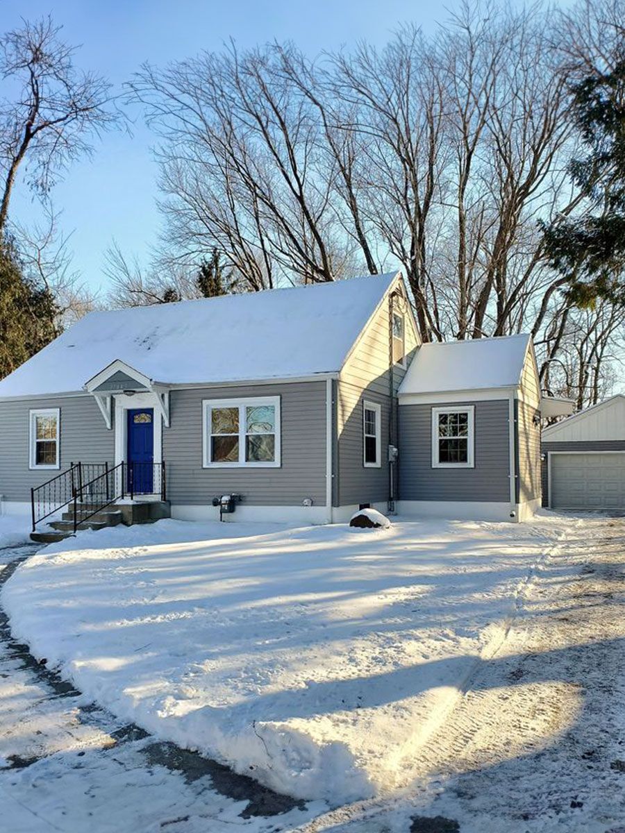 A house with a blue door is covered in snow.