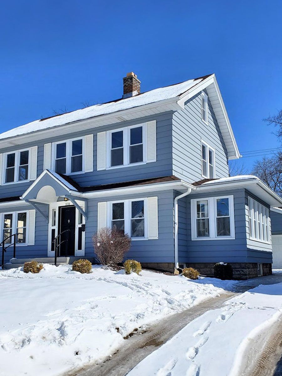 A large house with a lot of windows is covered in snow.