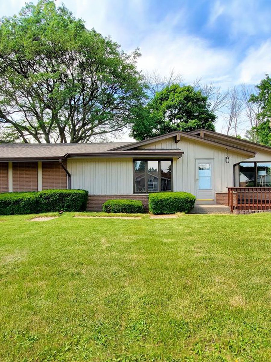 A white house with a large lawn in front of it.