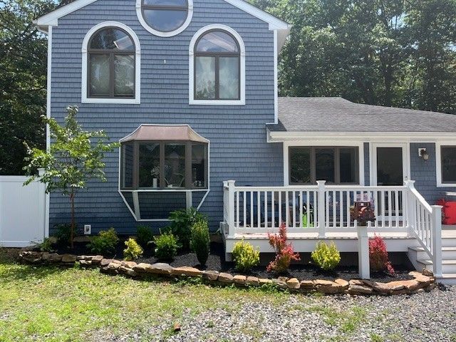 Patio seating area with brick pavers, surrounded by grass and a white wall.
