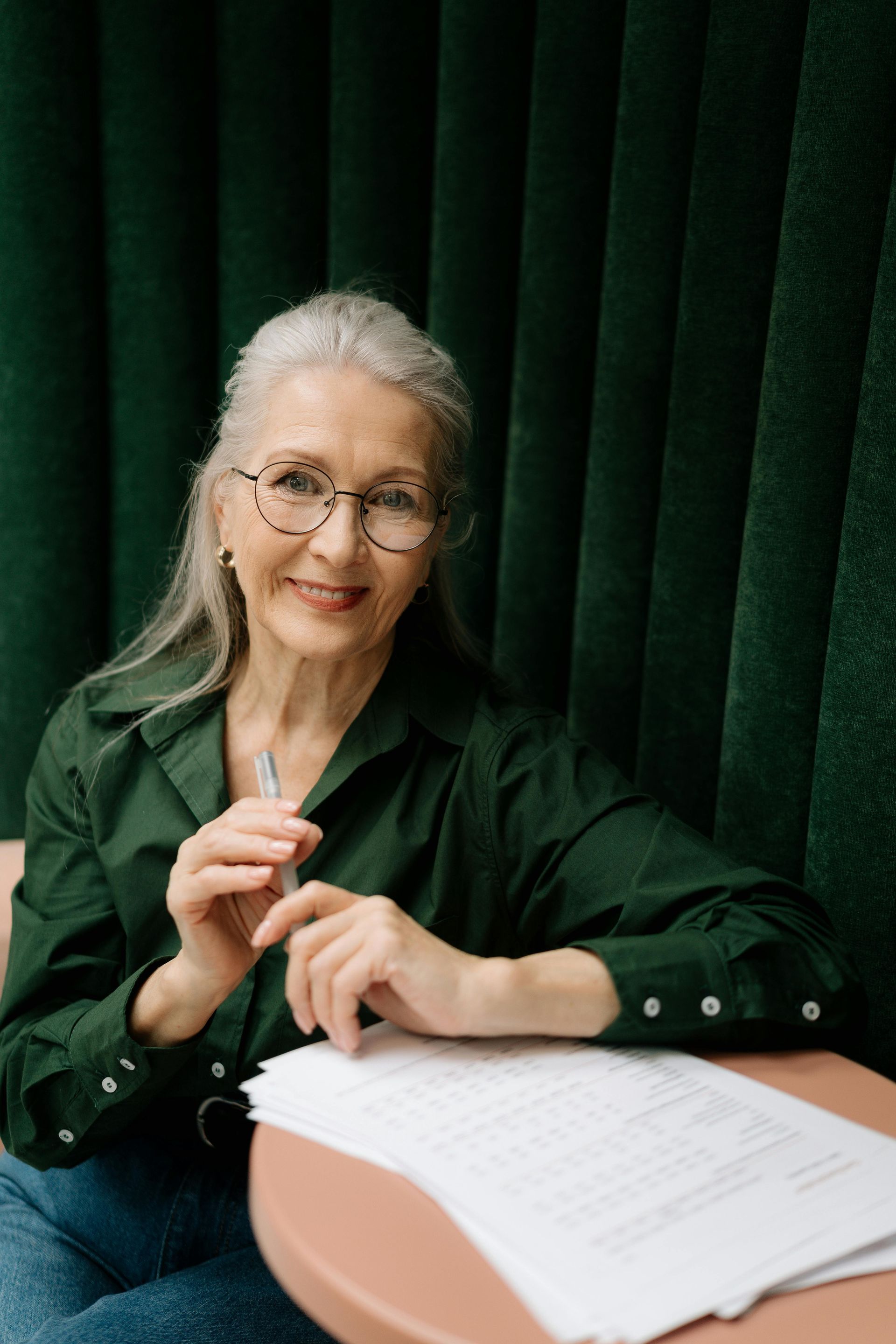 A woman is sitting at a desk holding a piece of paper.
