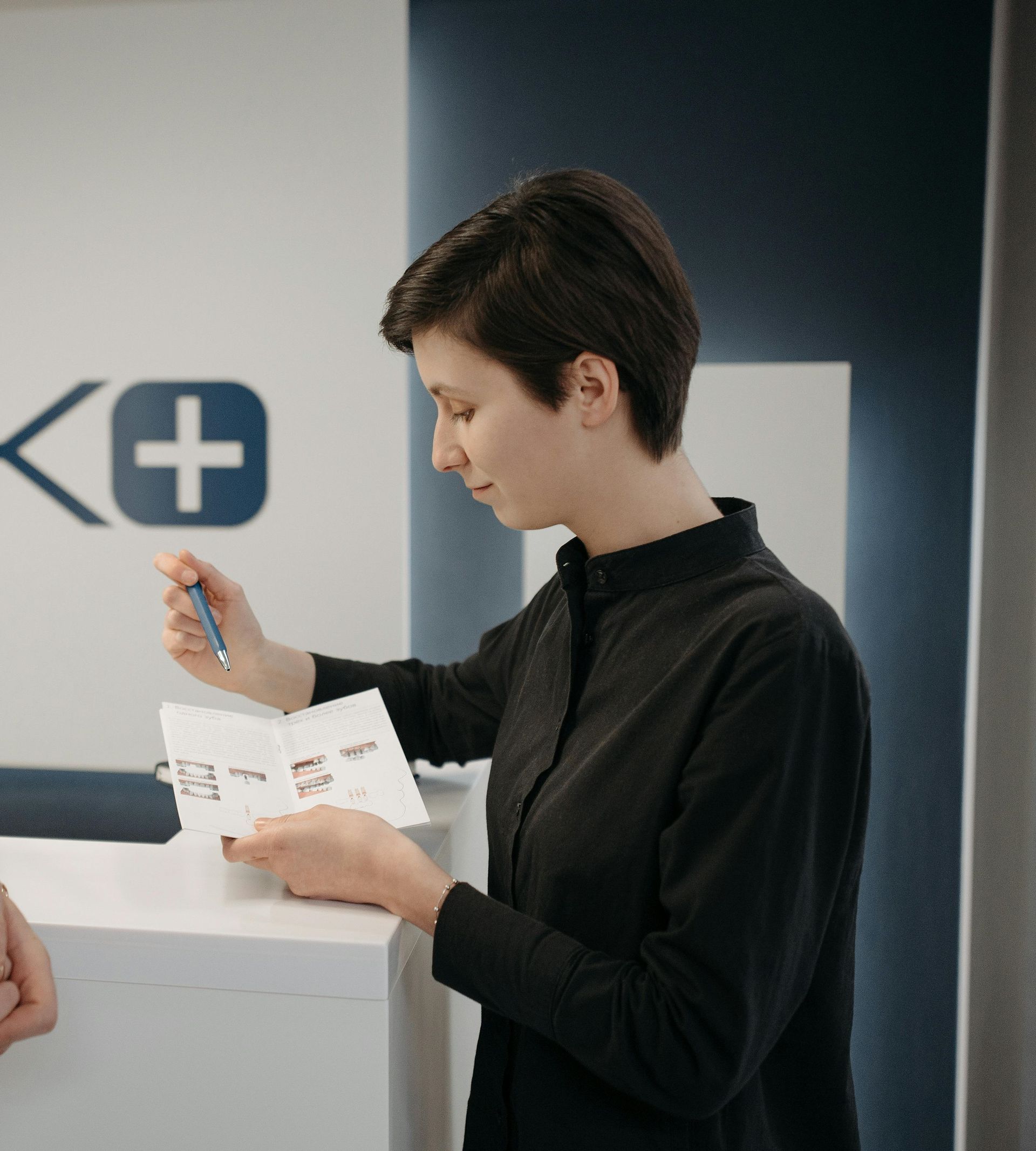 A woman is sitting at a desk holding a piece of paper.