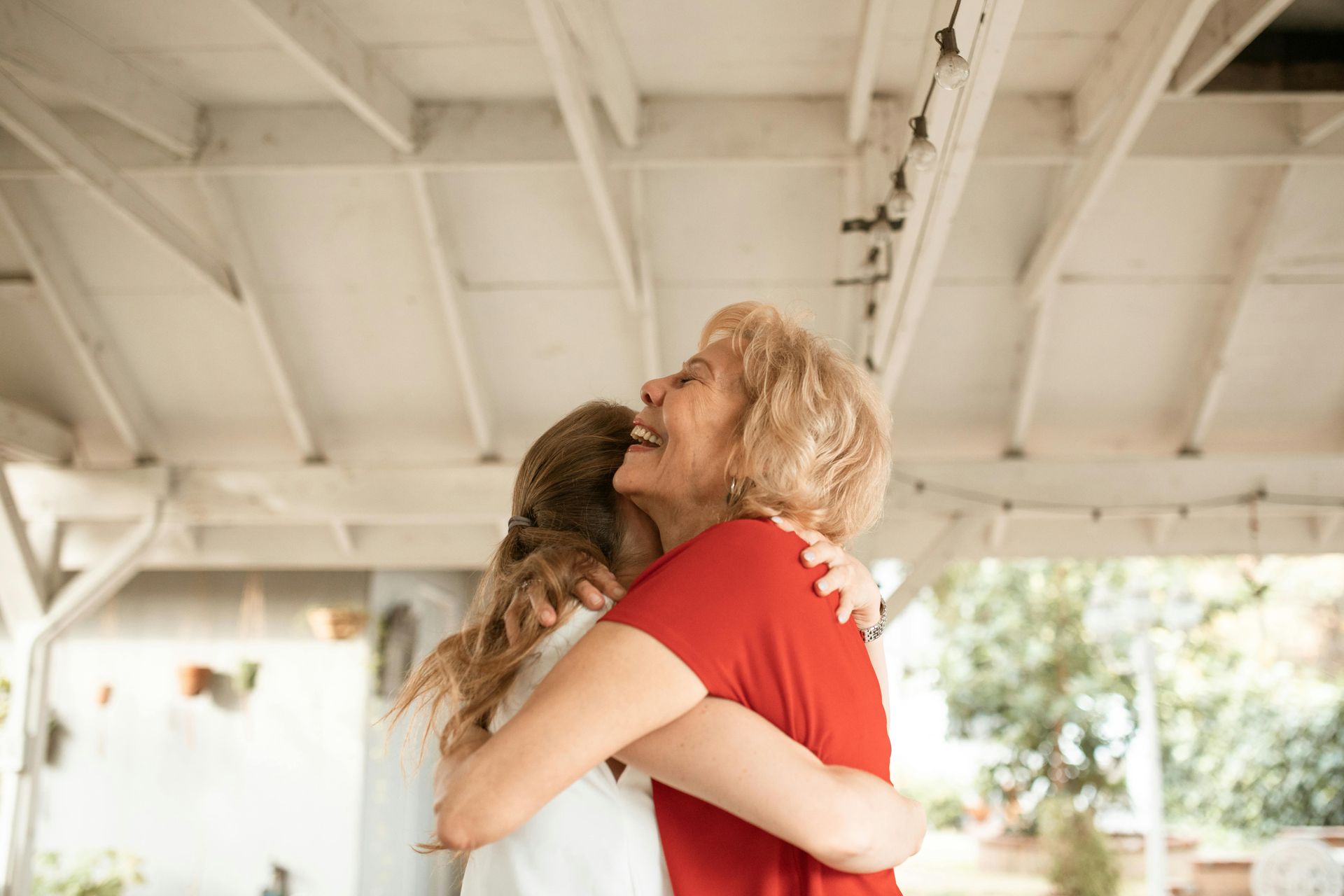 Two women are hugging each other under a white roof.