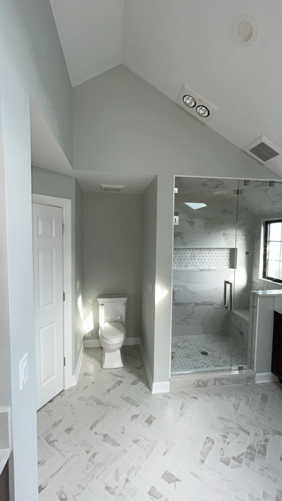 Bathroom with a toilet, shower, and light blue walls. Tile floor is visible.