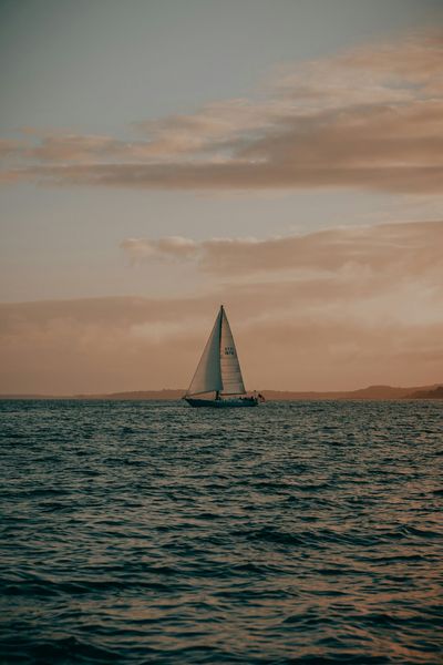 Sailboat on ocean under a dusky sky.