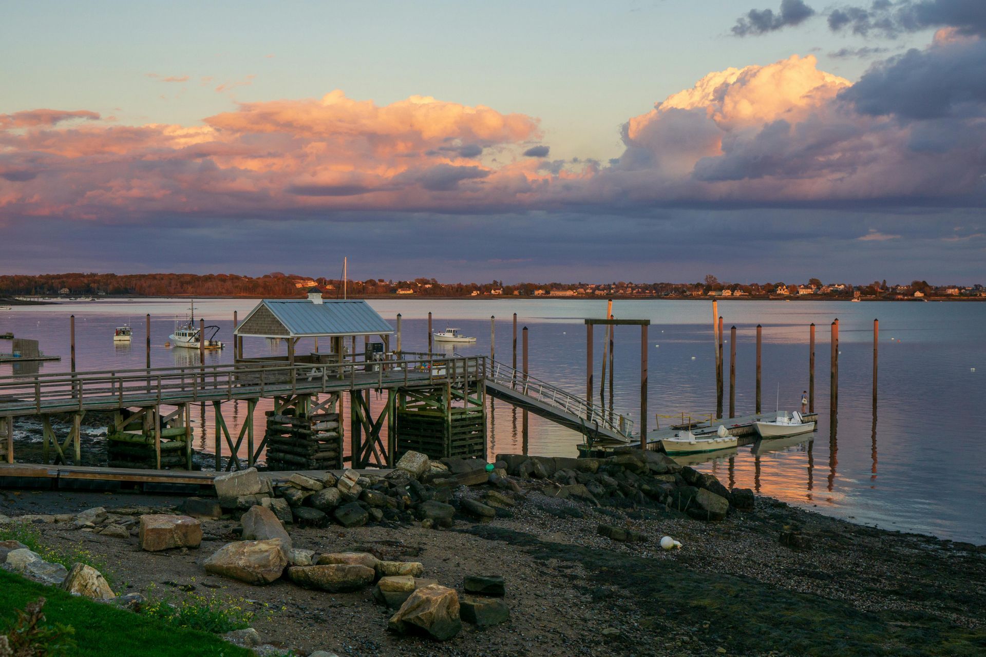 Sunset over a dock with boats, reflecting colors of pink and orange in the sky.