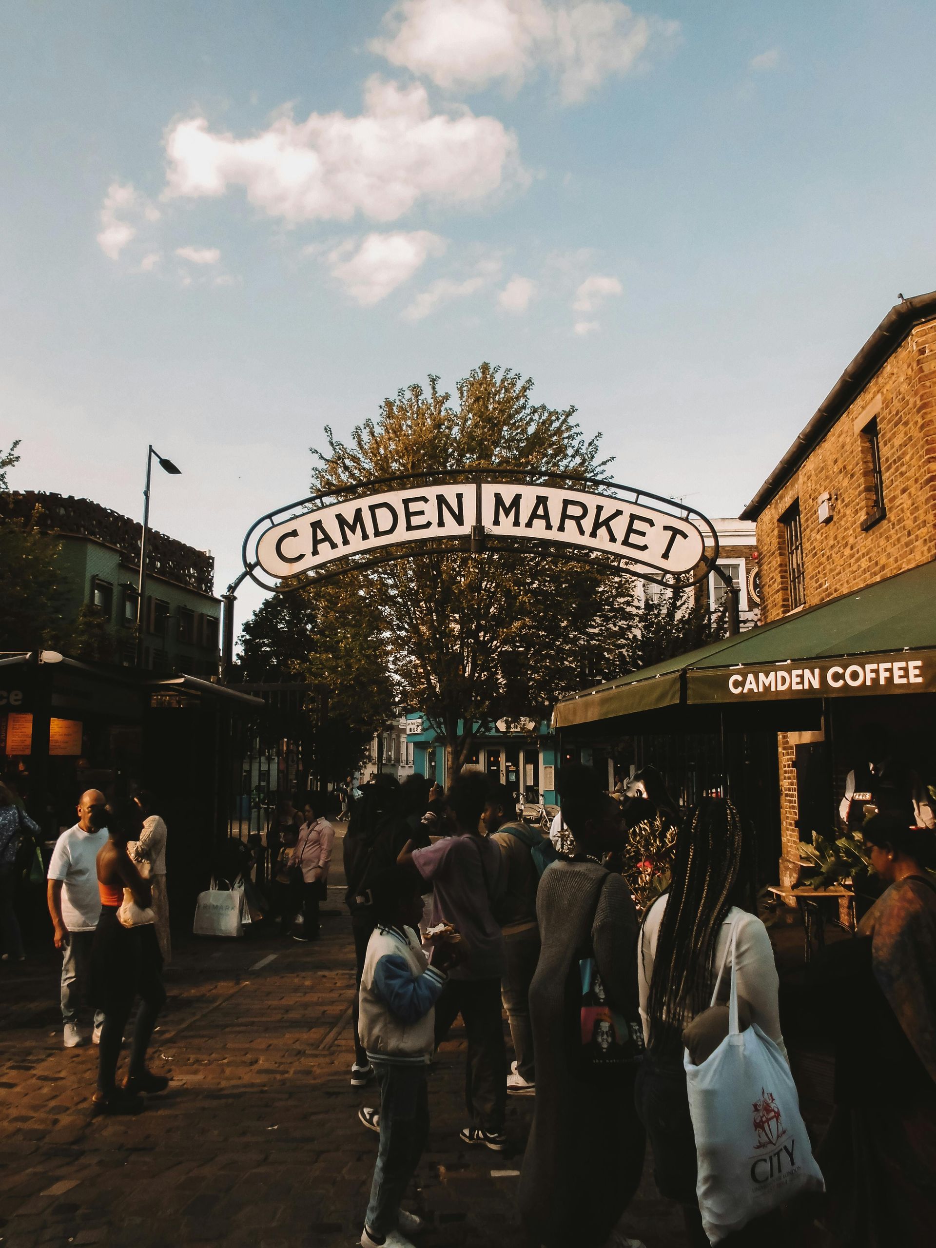Camden Market entrance with sign; people walking around, sunny day.