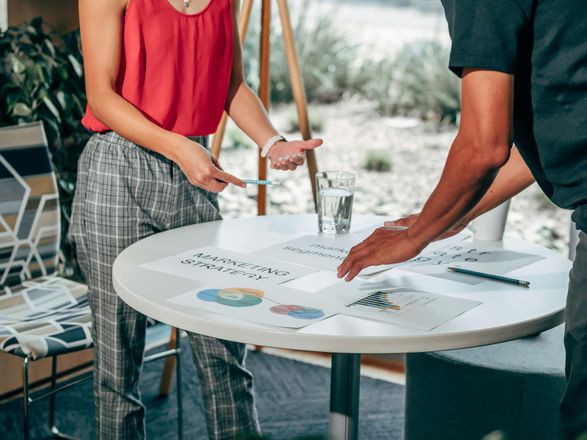 Two people reviewing papers on a round table in an office setting.