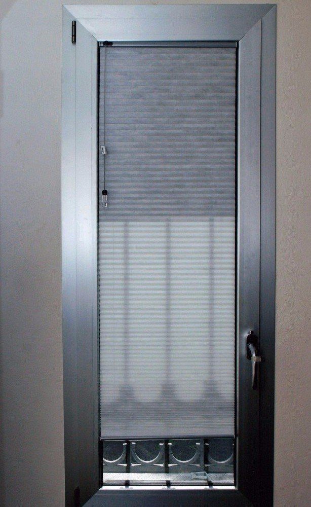 Finestra argentata con persiane chiuse e zanzariera.