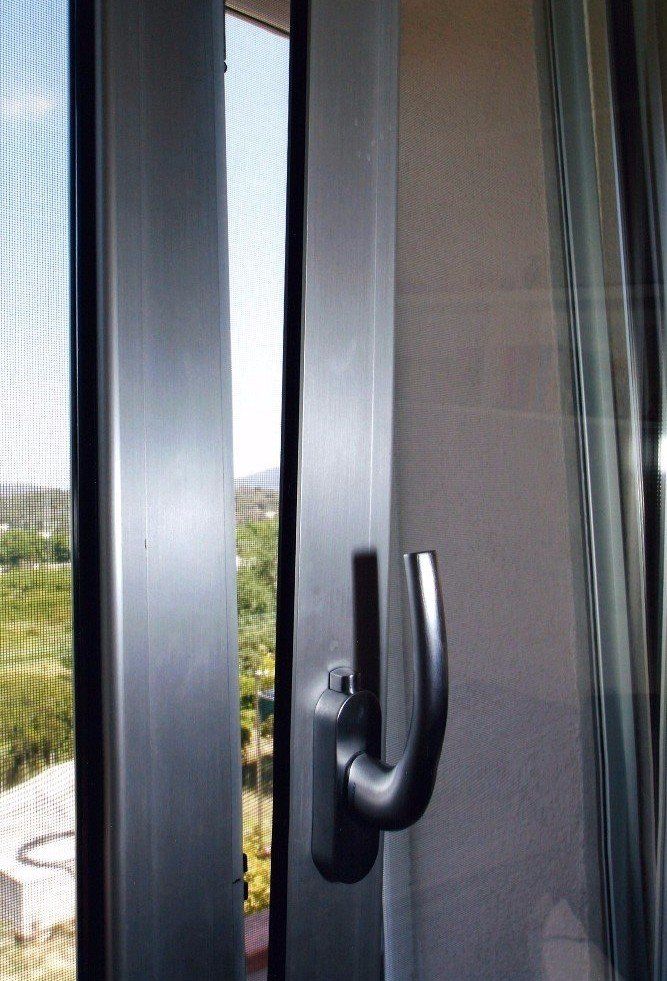 Finestra con maniglia in una stanza, parzialmente aperta con vista sull'esterno.