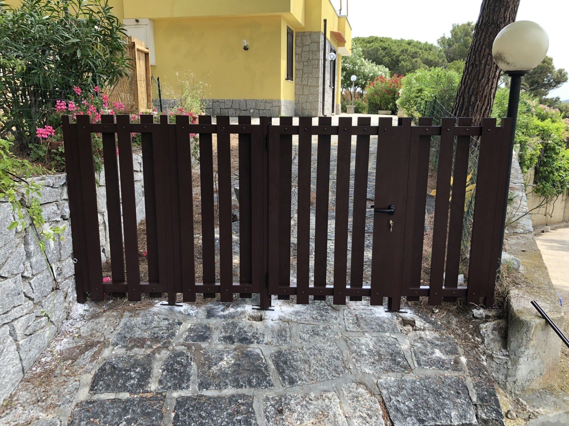 Cancello in legno marrone su gradini in pietra che conducono a un edificio giallo.
