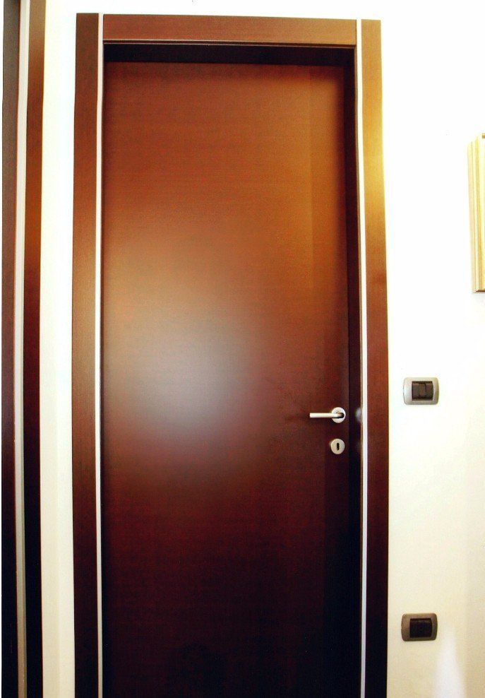 Porta in legno marrone scuro con ferramenta argentata e finiture bianche.