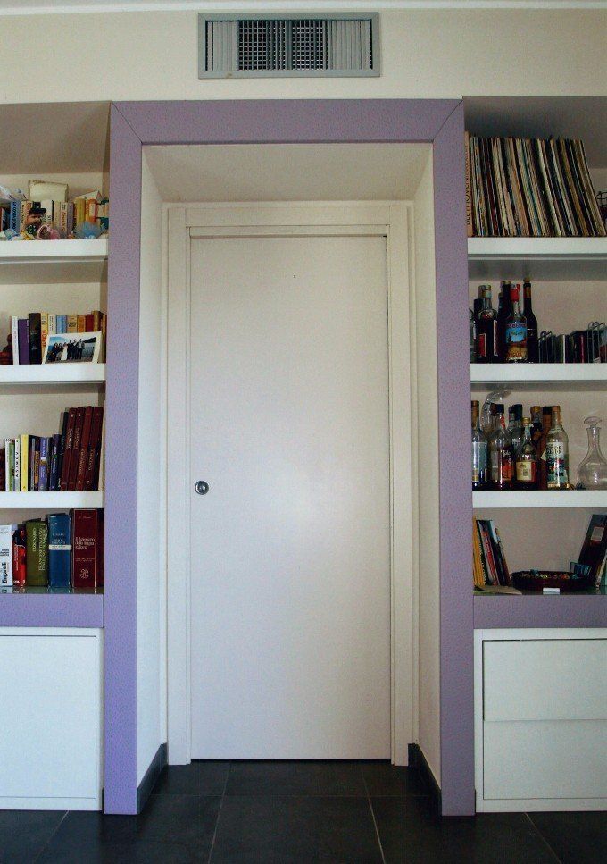 Porta incorniciata in viola, fiancheggiata da librerie con libri e armadietti.