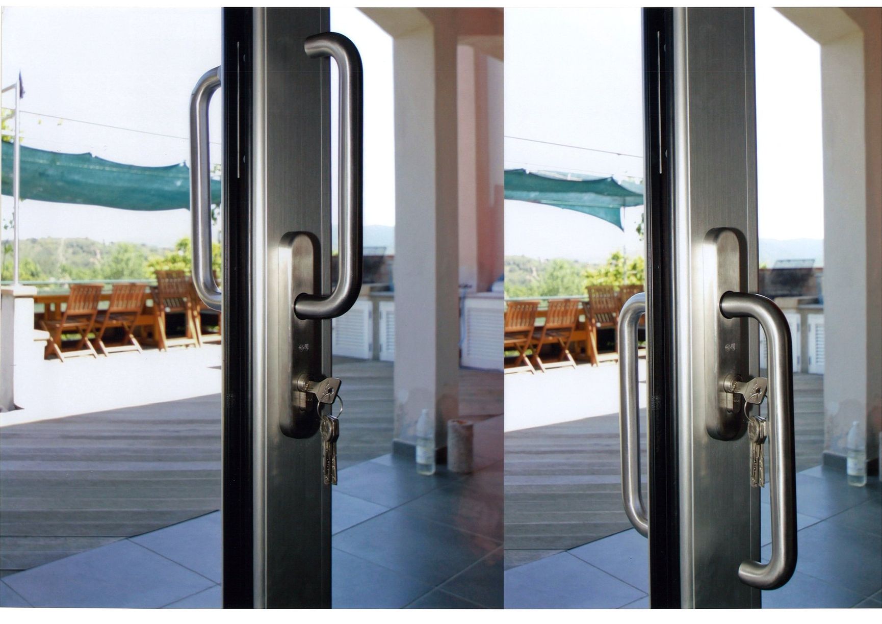 Due porte in vetro con maniglie in metallo, una chiusa con chiavi, l'altra che si apre su un terrazzo con tavoli e sedie.