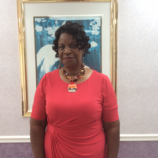 A woman in a red dress is standing in front of a picture.