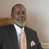 A man in a suit and tie is sitting in a chair.