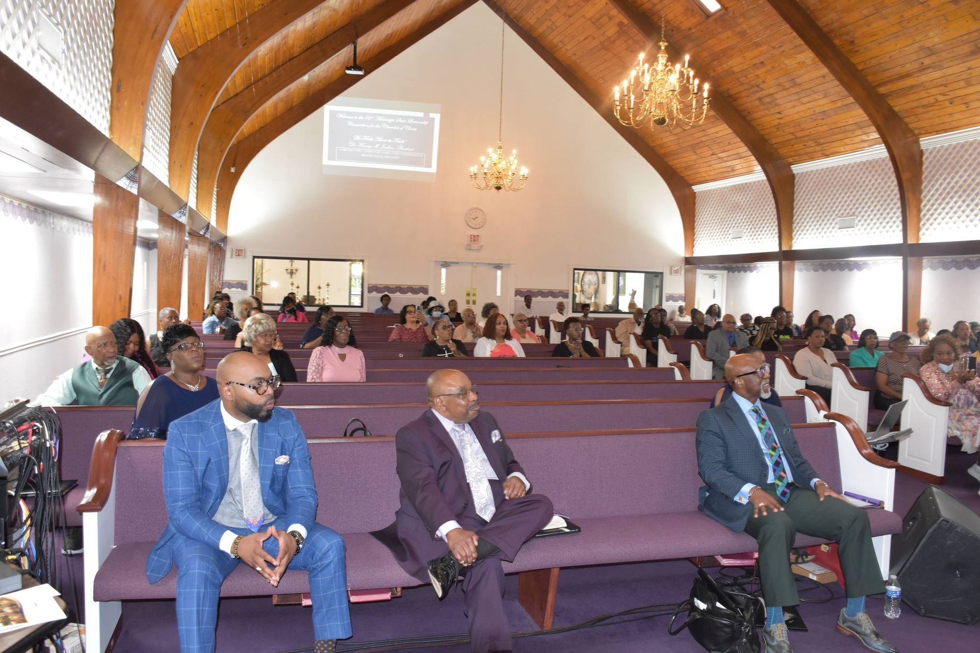 A group of people are standing in a room with tables and chairs.