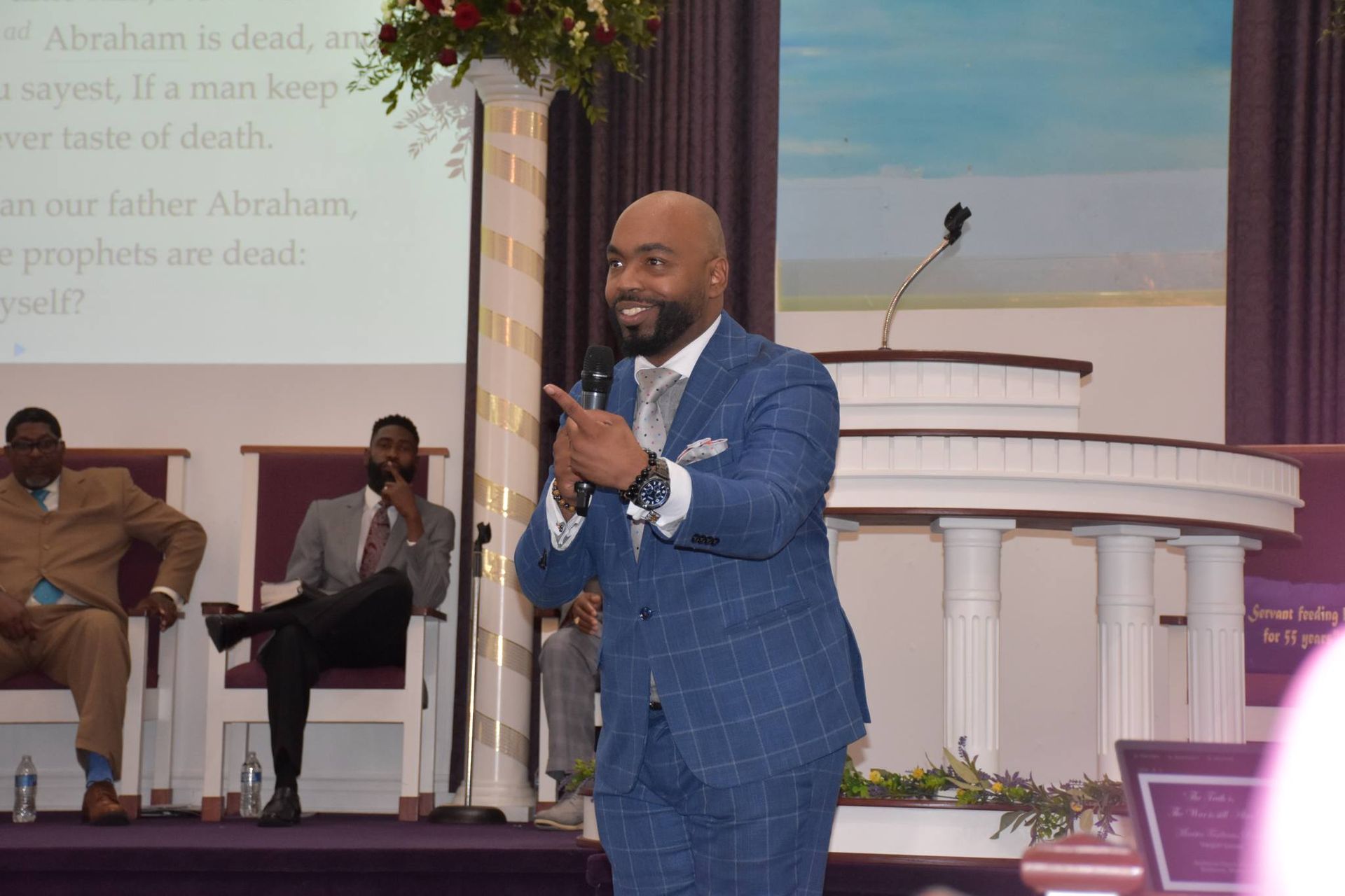 A man in a suit is standing in front of a microphone in a church.