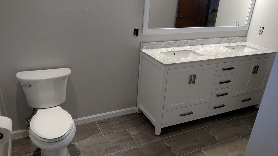 A bathroom with a toilet , sink and mirror.