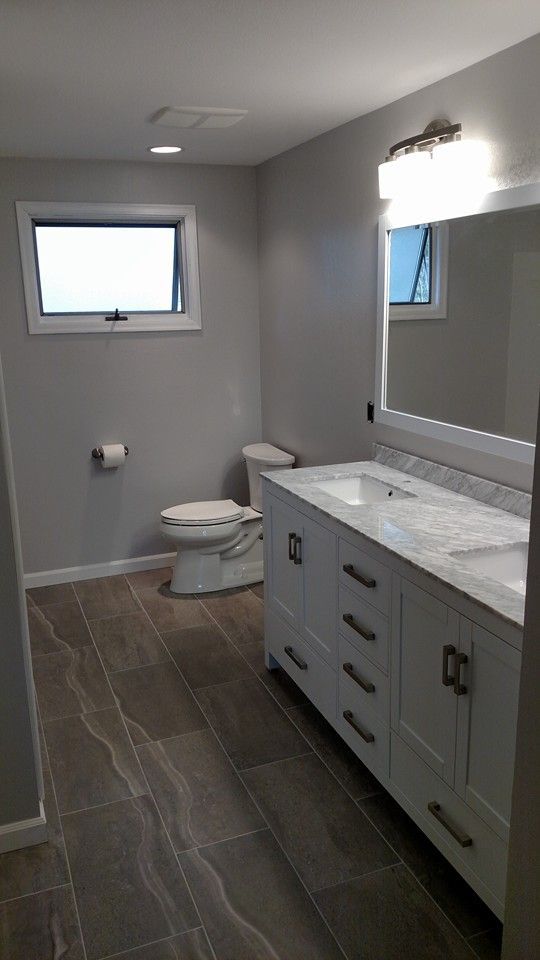 A bathroom with a toilet , sink and mirror.