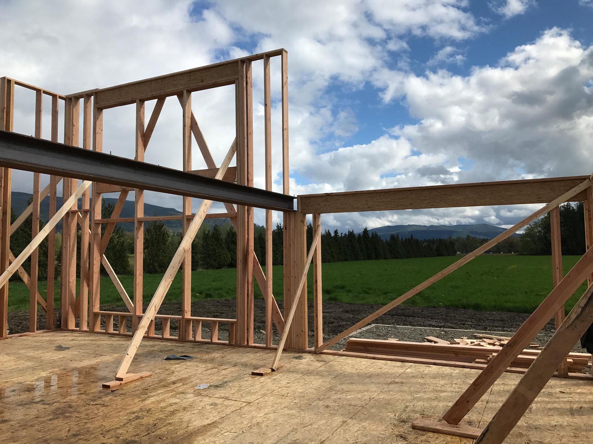 A wooden structure is being built in a field with mountains in the background.