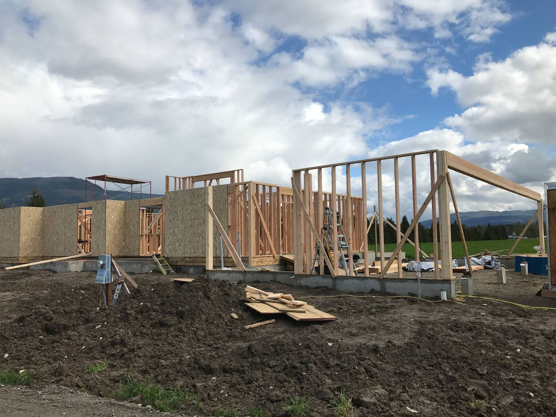 A house is being built in a dirt field with mountains in the background.