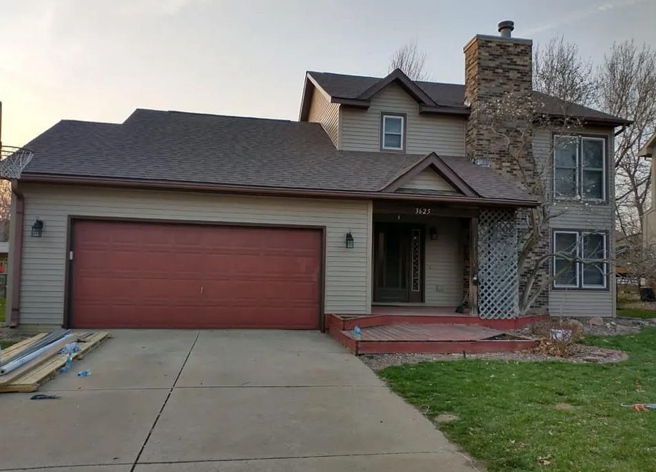 A large house with a red garage door and a stone chimney.