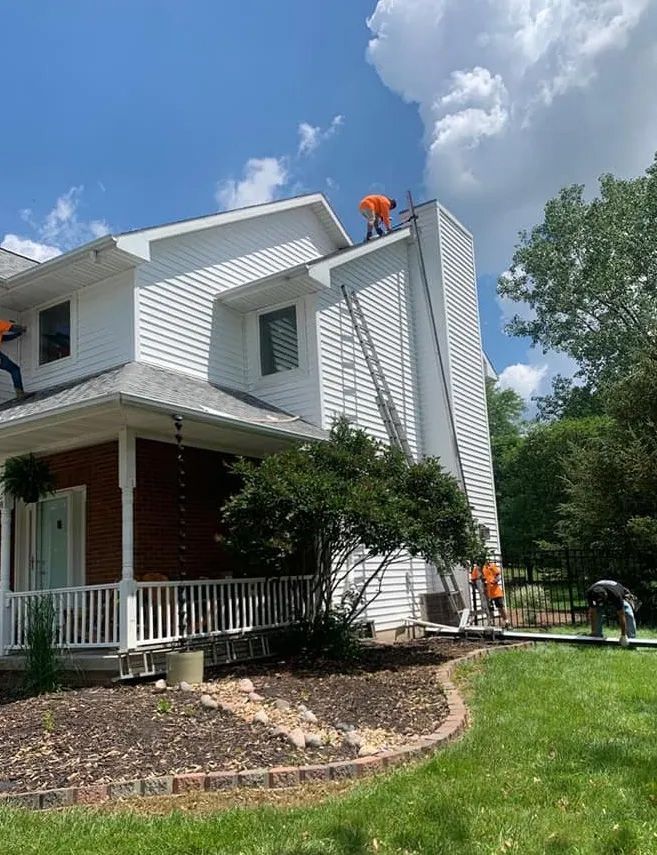 A group of people are working on the roof of a house.