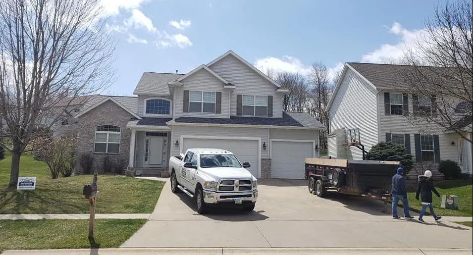 A white truck is parked in front of a large house.