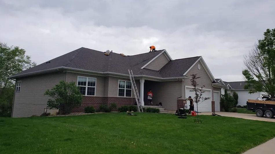 A couple of men are working on the roof of a house.