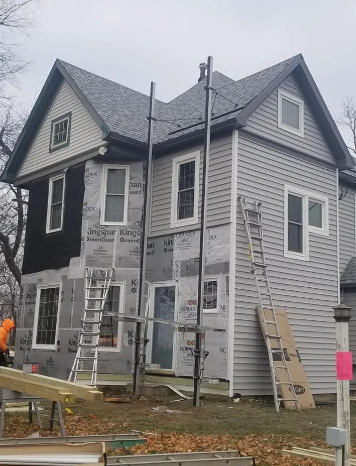 A house that is being remodeled with a ladder on the side of it.