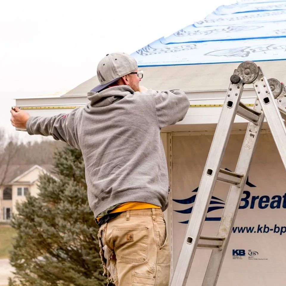 A man standing on a ladder measuring a roof