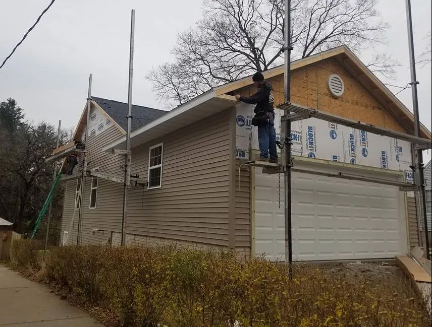 A man is working on the side of a house.