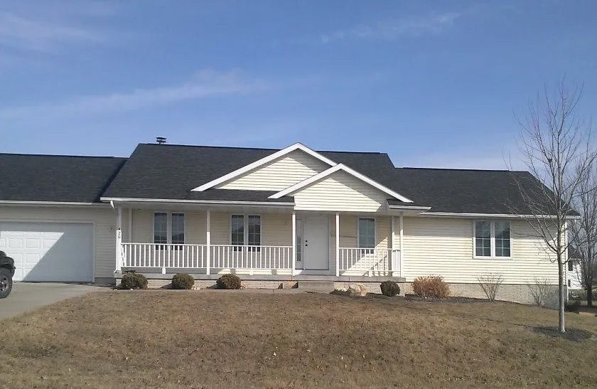 A white house with a black roof and a porch
