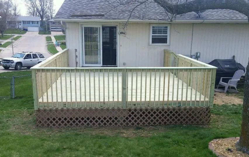 A wooden deck is sitting in front of a house.
