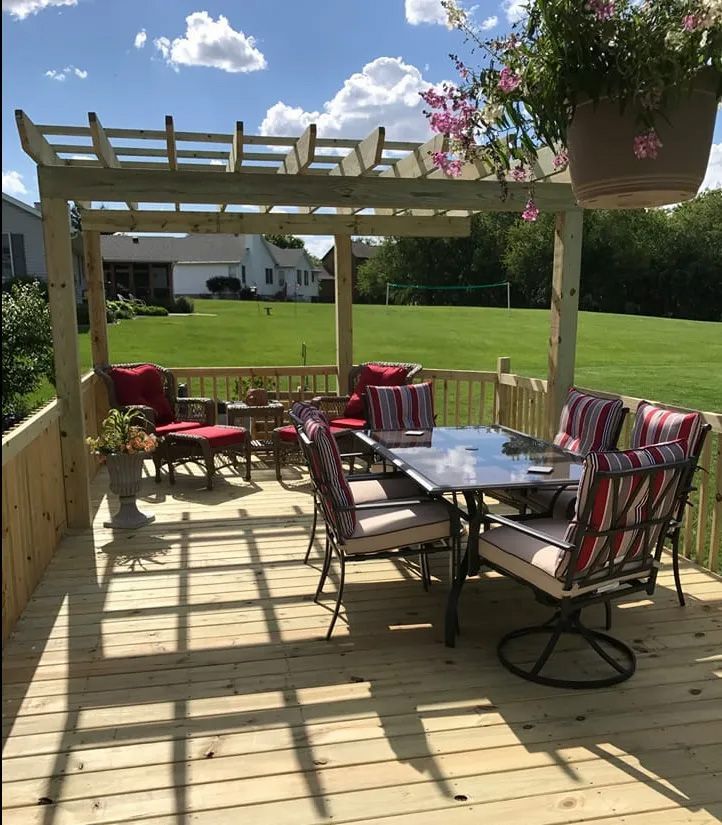 A wooden deck with a table and chairs under a pergola
