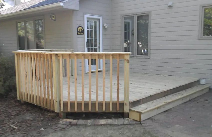 A wooden deck is sitting in front of a house.