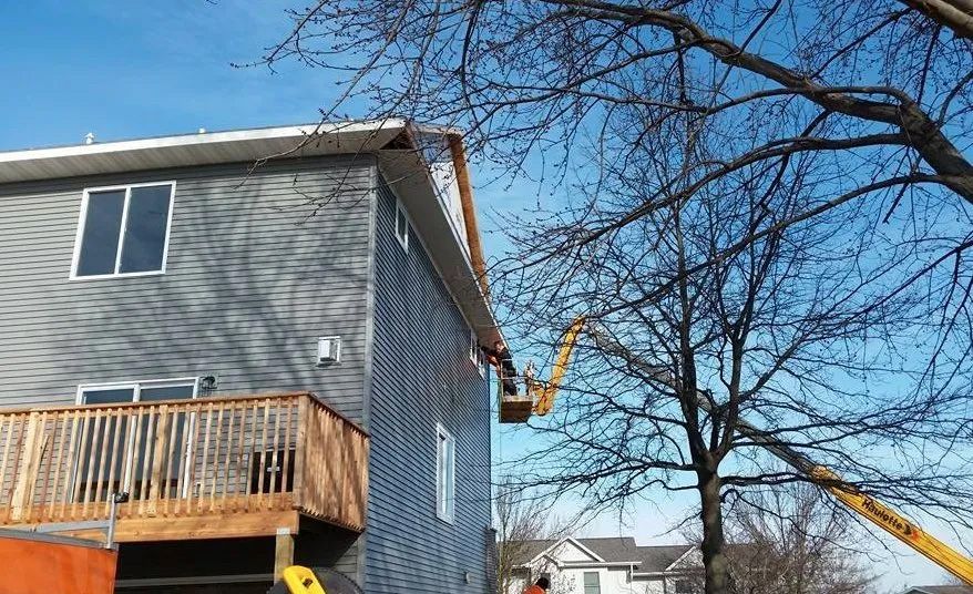 A man is working on the roof of a house with a crane.