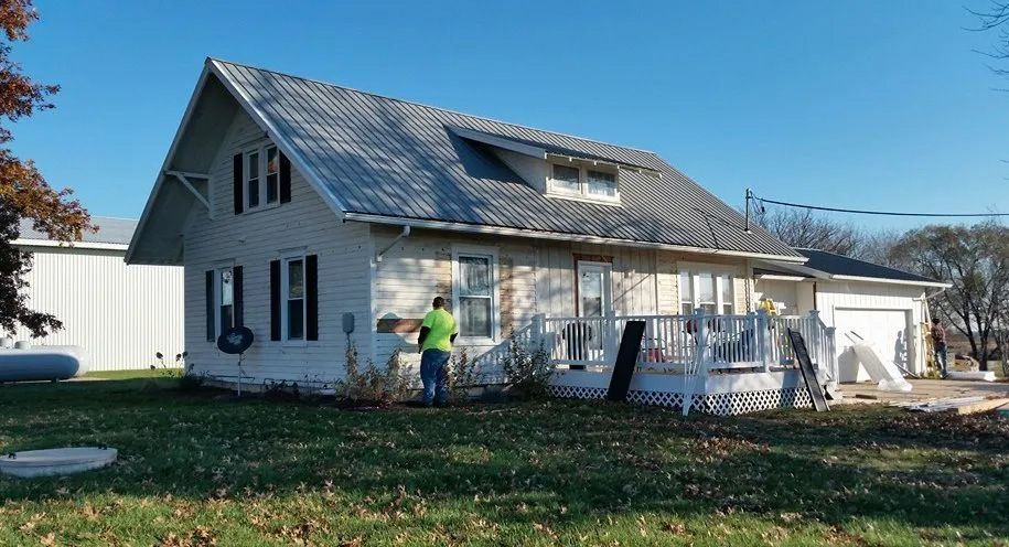 A man is standing in front of a white house.