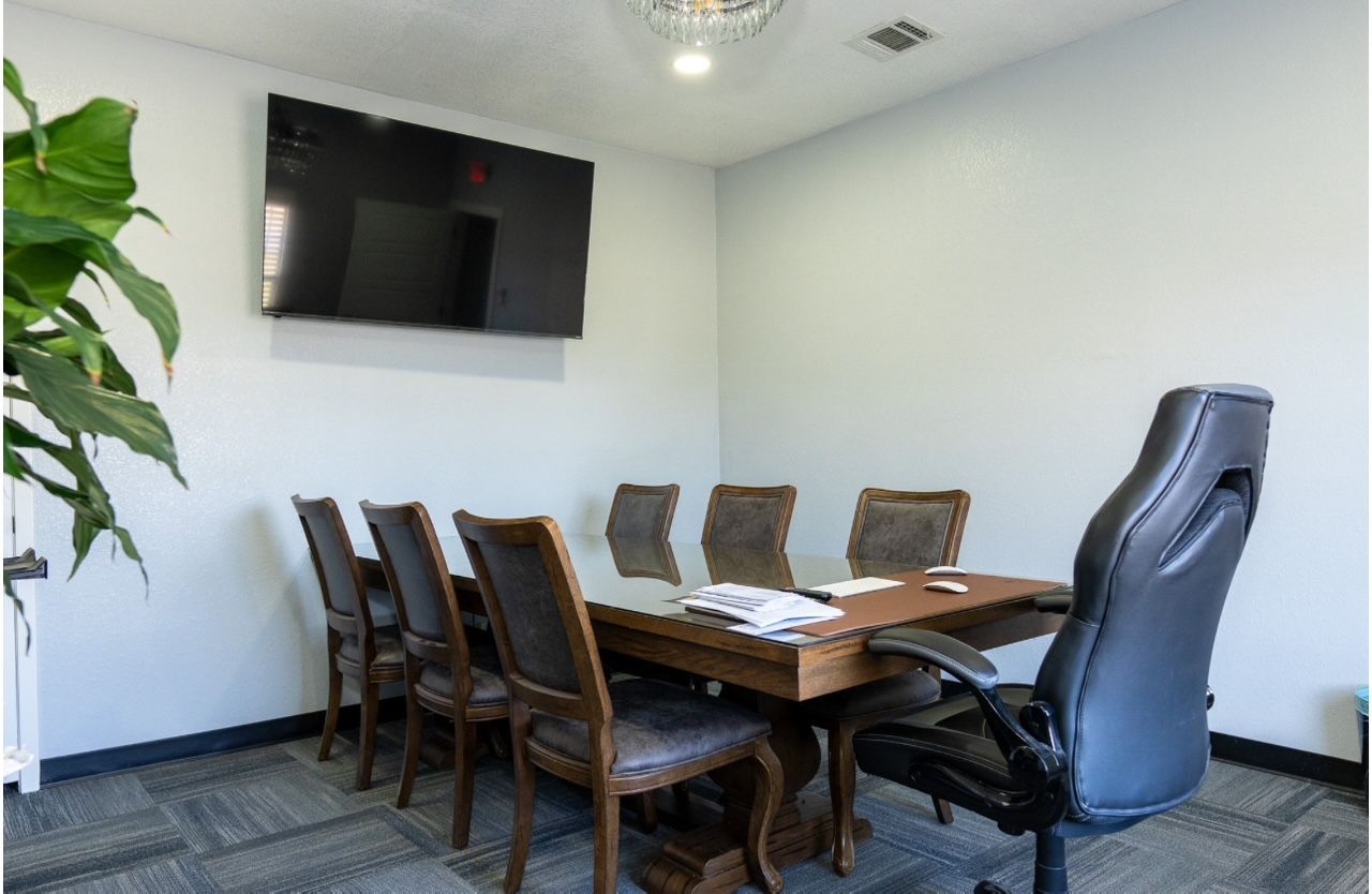 A conference room with a table and chairs and a flat screen tv on the wall.