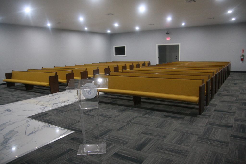 An empty church with rows of wooden benches and a podium.
