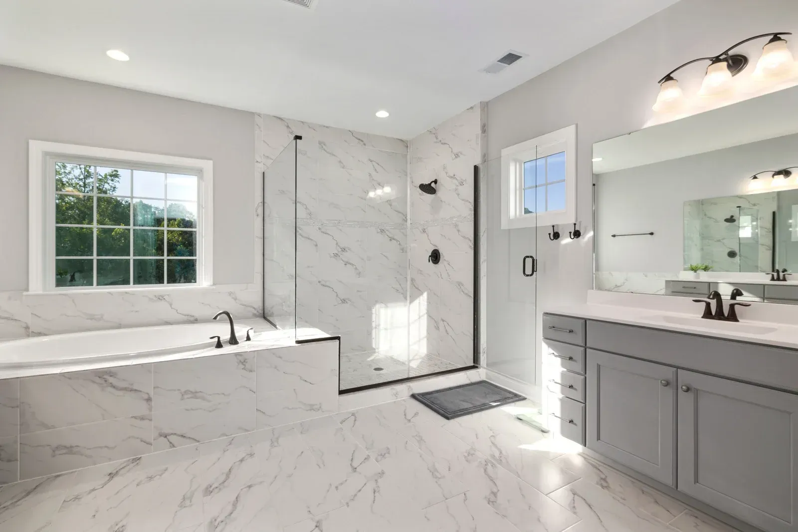 Bright, modern bathroom with marble tile, a soaking tub, and a glass-enclosed shower.